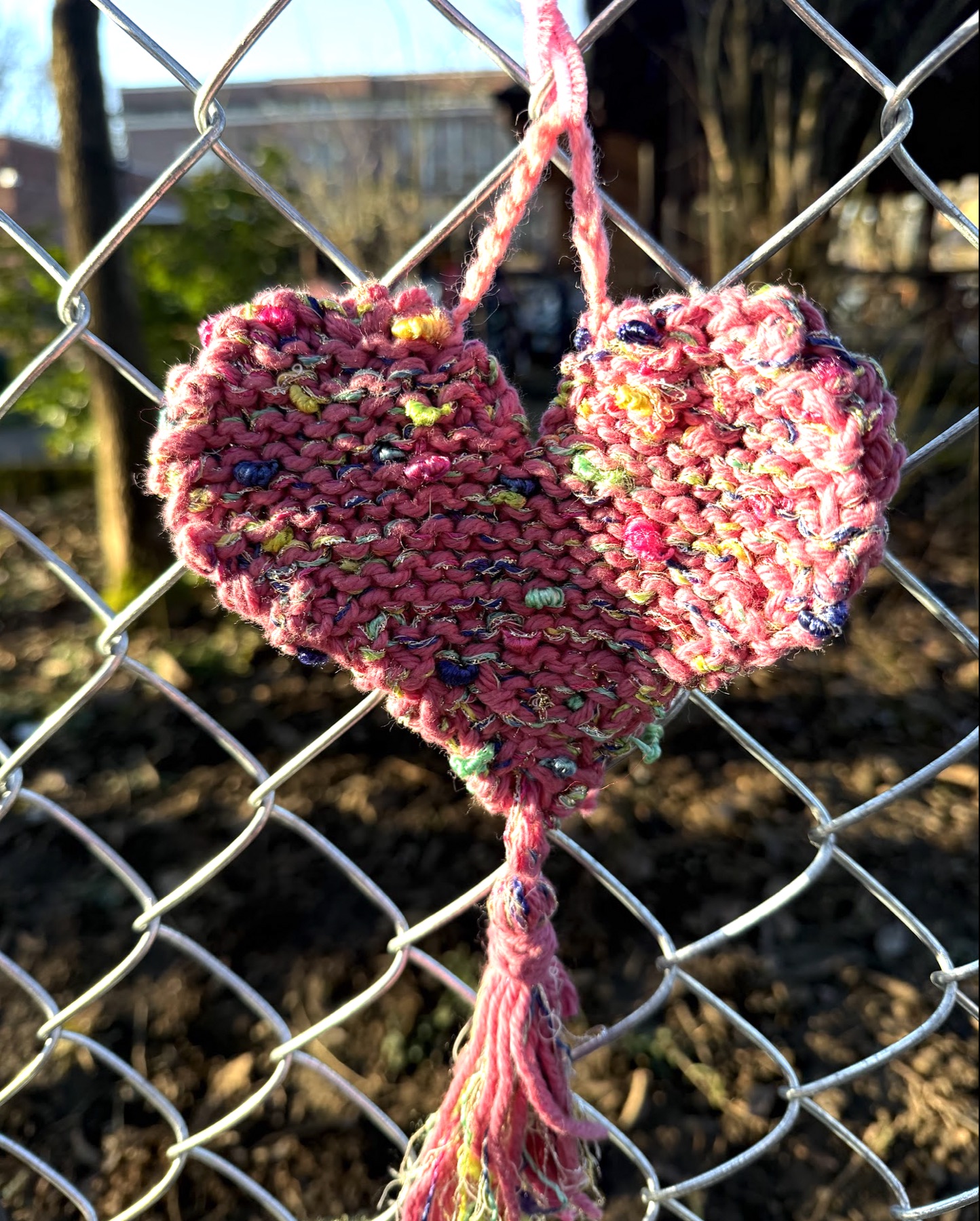 Hand-knit heart hanging on the schoolyard fence