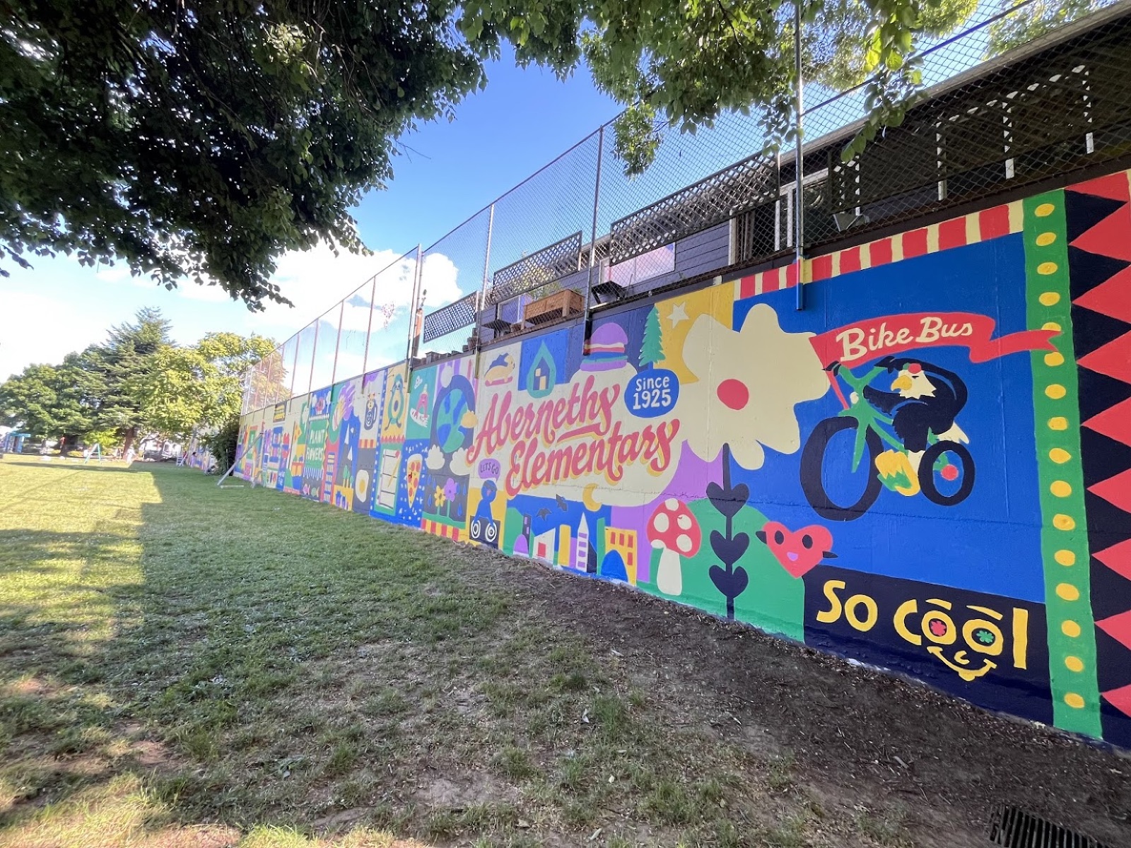The Abernethy mural along the field wall — 'Abernethy Elementary,' 'Bike Bus,' and 'So Cool'